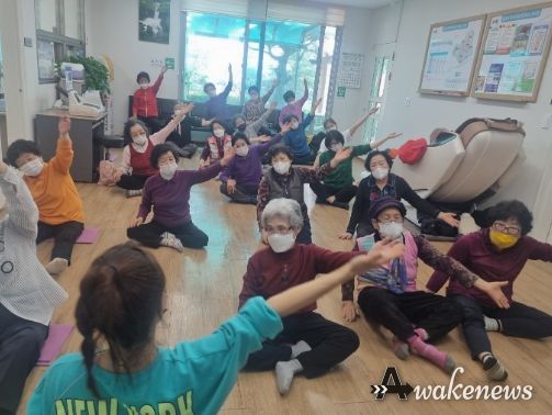 전문강사의 동작을 따라 왼팔을 높이 든 경로당 어르신들