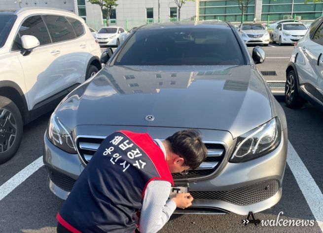 용인시 체납관리단이 관내 한 주차장에서 차납 차량 번호판을 영치하고 있는 모습