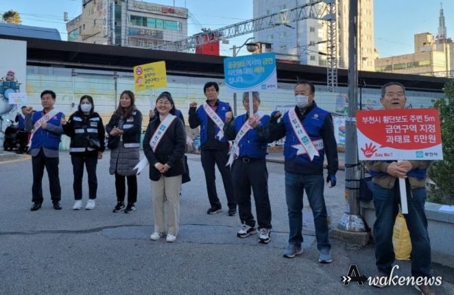 금연 어깨띠를 두르고 피켓을 이용해 흡연의 심각성을 알리고 있다
