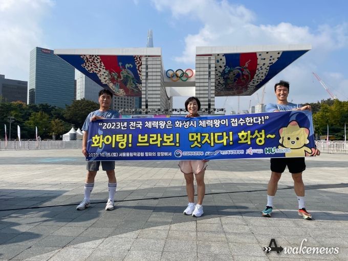 올림픽공원 평화의 광장 앞에서 화성시 체력왕 대표로 전국대회에 참여한 시민 3명이 현수막을 사진을 찍고 있다. (화성도시공사 제공)