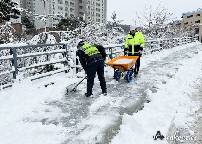 시 관계자가 인도에 쌓인 눈을 치우며 소형 제설장비로 염화칼슘을 뿌리고 있다