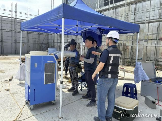 공사장 현장 근로자들이 그늘막에서 이동식 에어컨으로 더위를 식히고 있다.